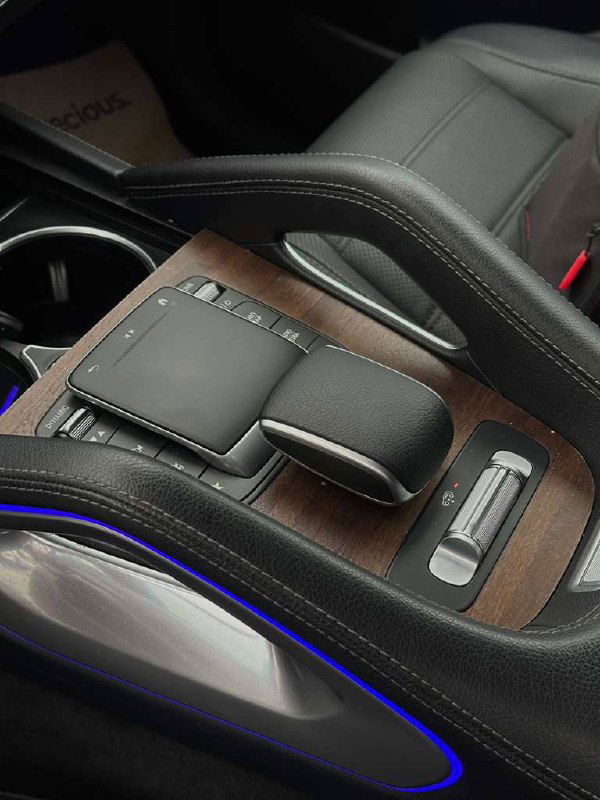 Центральный тоннель Mercedes GLE 450: деревянная декоративная вставка, сенсорный тачпад, селектор АКПП и фиолетовая атмосферная подсветка по контуру.