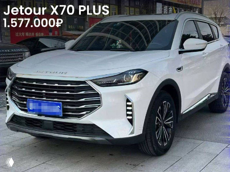Jetour X70 PLUS белого цвета, крупный вид передней части и решётки, автомобиль на стоянке дилерского центра, цена 1.577.000₽.