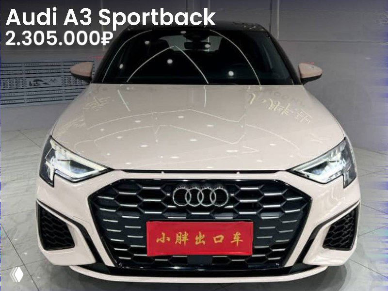 Фото Audi A3 Sportback белого цвета, крупный план передней части кузова в автосалоне; цена 2.305.000₽, без окрасов.