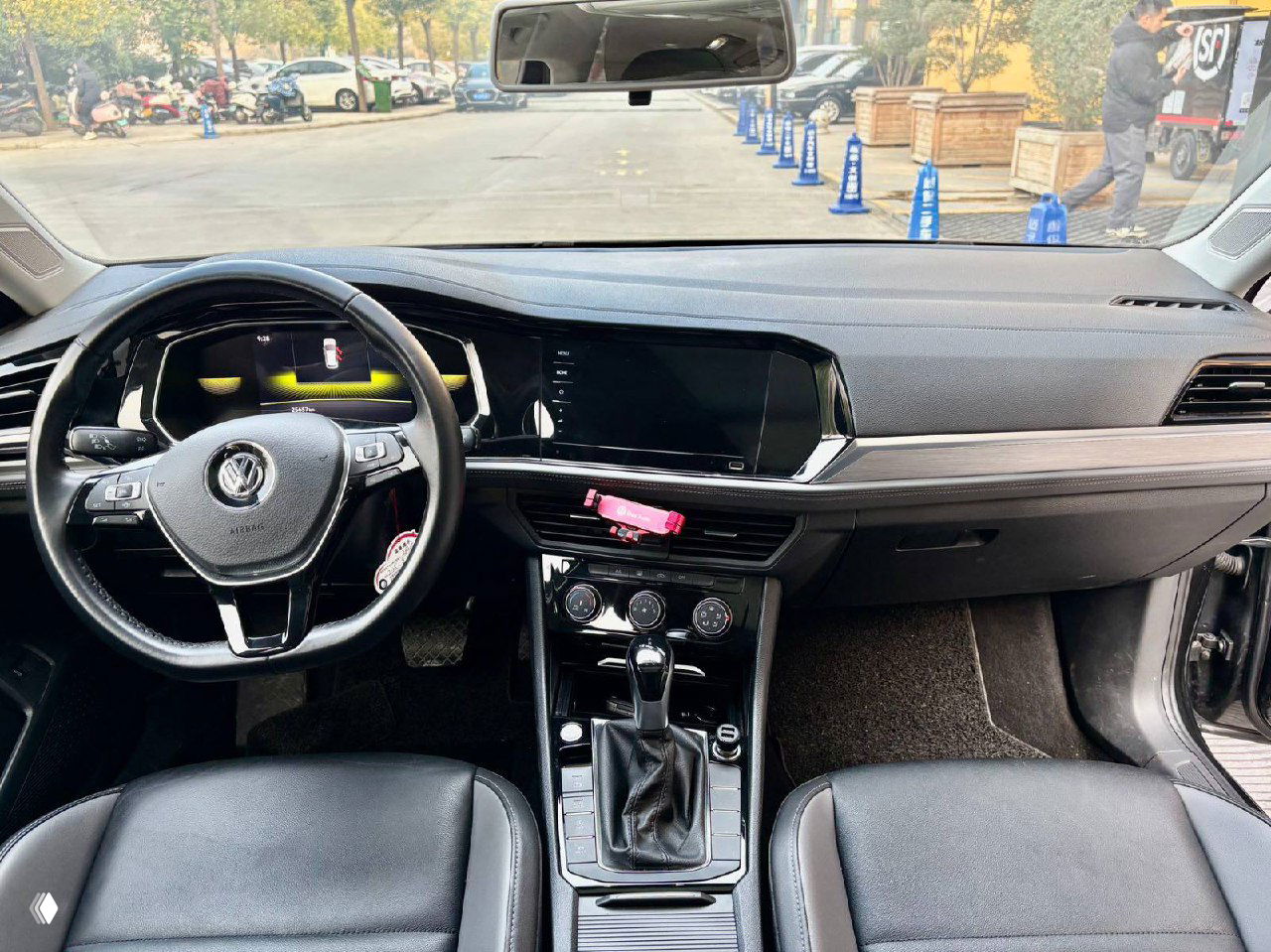 Интерьер Volkswagen Sagitar: вид на панель приборов, руль с логотипом VW, мультимедийный экран и центральную консоль с селектором робота.