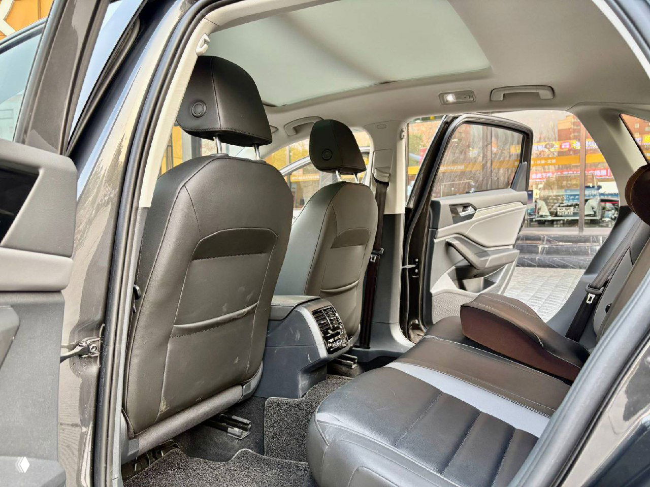 Задний ряд салона Volkswagen Sagitar с кожаными сиденьями, вид с открытой задней двери, пространство для ног и общее состояние заднего сиденья.