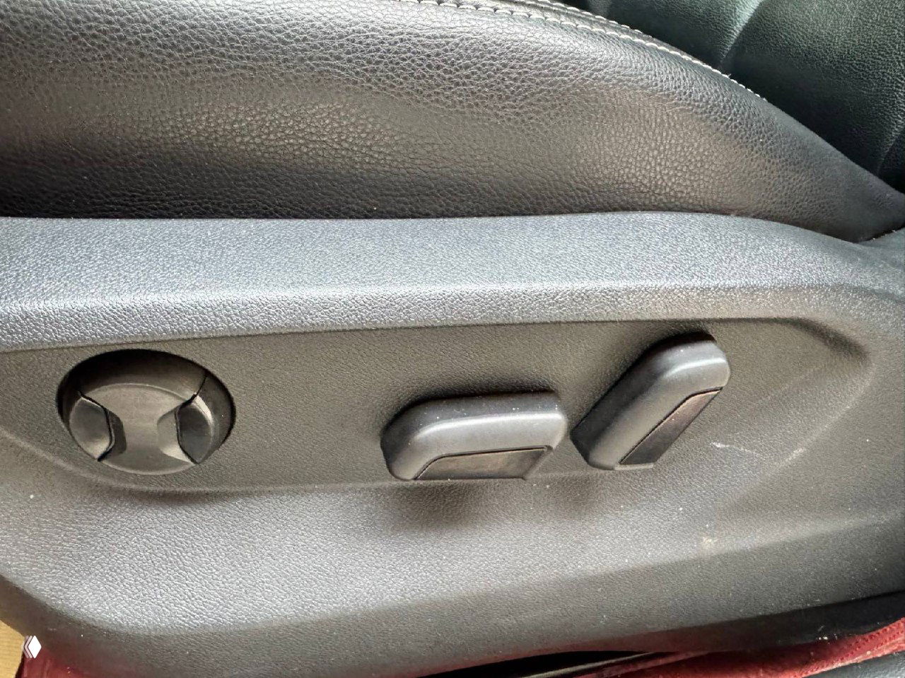 Панель регулировок сидения и боковая часть кресла водителя Audi Q2L, электрические регуляторы и незначительные следы использования на пластике.
