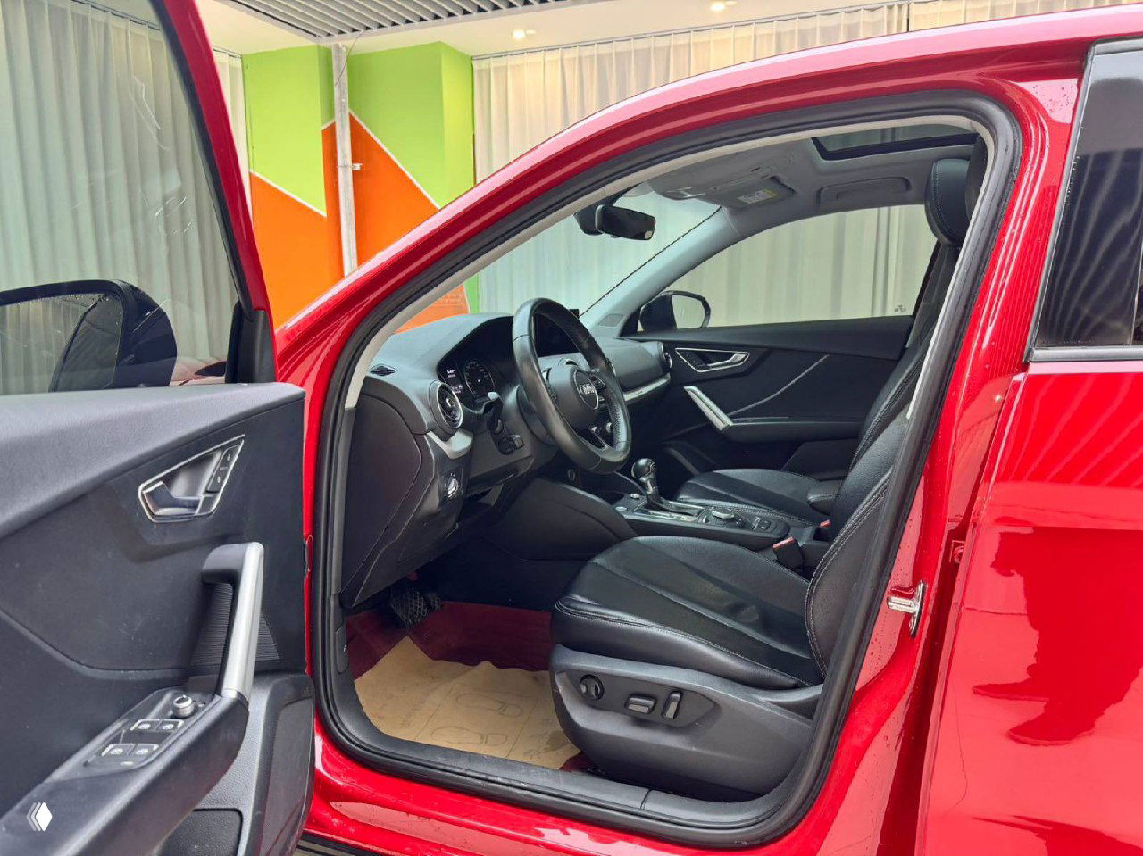 Интерьер Audi Q2L: переднее водительское кресло, рулевое колесо и центральная консоль с коробкой передач, общая картина состояния салона.