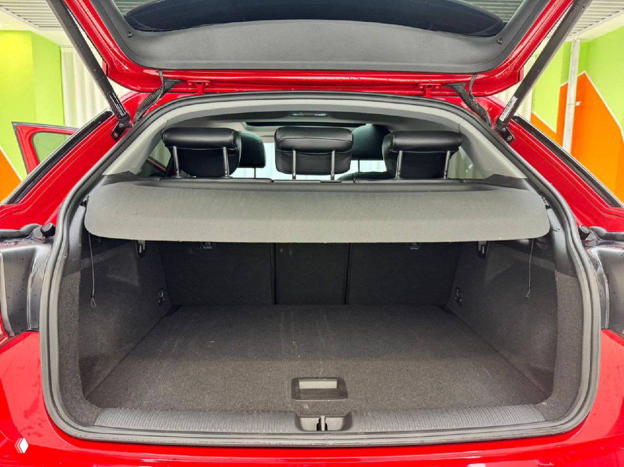 Открытый багажник Audi Q2L с чёрным ковровым покрытием и крышкой багажника в поднятом положении, просторный отсек без груза.