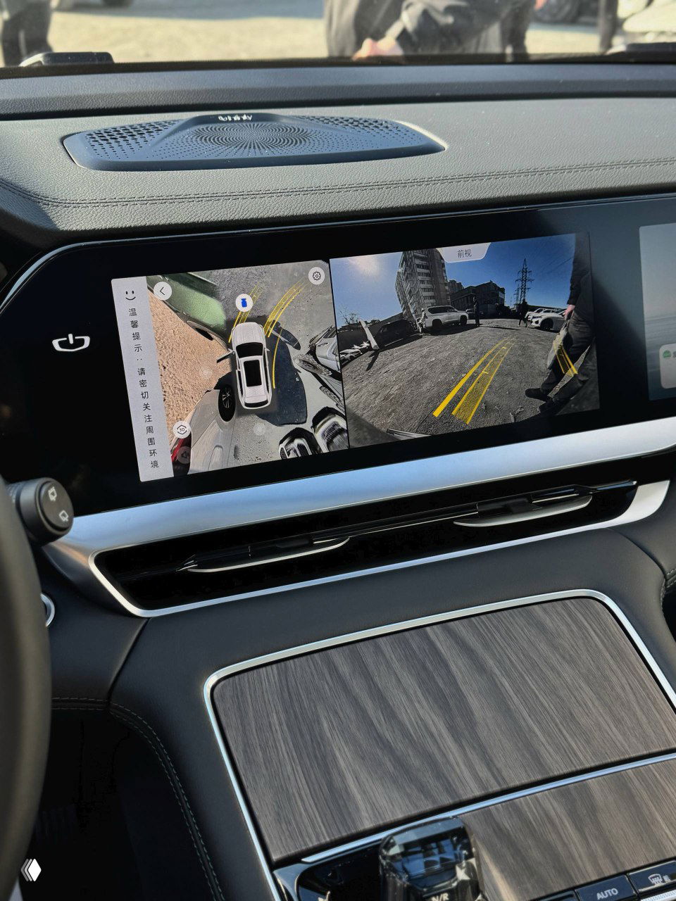 Центральный панорамный дисплей Geely Monjaro с изображением кругового обзора камеры, видна разметка парковки и интерфейс мультимедиа на экране автомобиля.