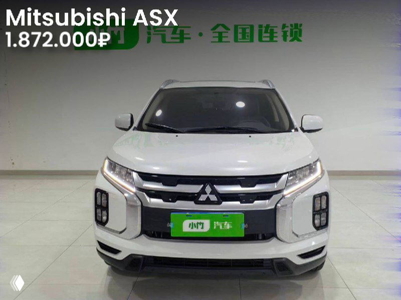 Фронтальный вид белого Mitsubishi ASX 2021 в выставочном зале, крупный план решётки, пробег 24.900 км, цена 1.872.000₽.