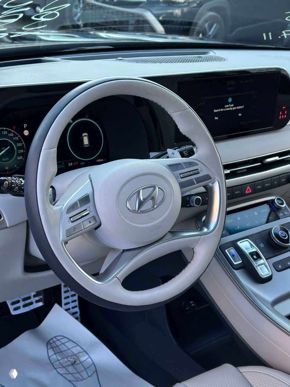 Рулевое колесо и цифровая панель приборов Hyundai Palisade — светлая кожаная отделка, эмблема Hyundai и большой экран мультимедиа.