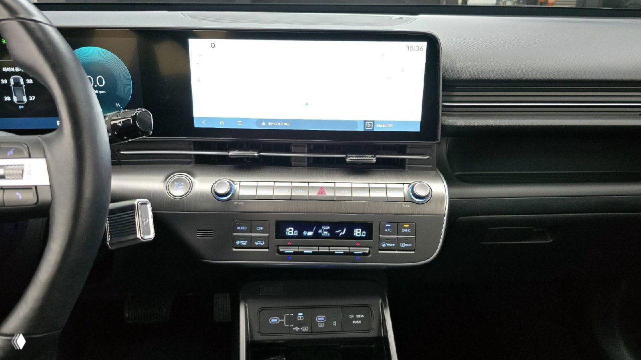 Центральная консоль Hyundai Kona: элементы управления климатом, медиакнопки, шайба селектора и область беспроводной зарядки в нижней части панели.