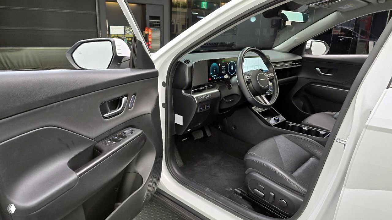 Открытая передняя дверь Hyundai Kona, вид на водительское место: сиденье, кнопки управления на двери и порог, демонстрация общего состояния салона.