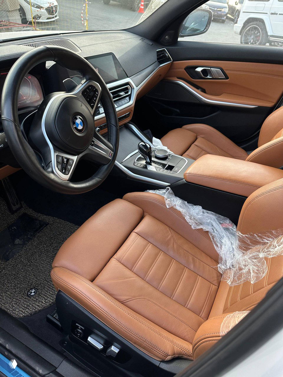 Водительское место BMW 340i: коричневый кожаный салон, руль с логотипом BMW, центральная консоль и экран мультимедиа; видна заводская отделка и эргономика панели.