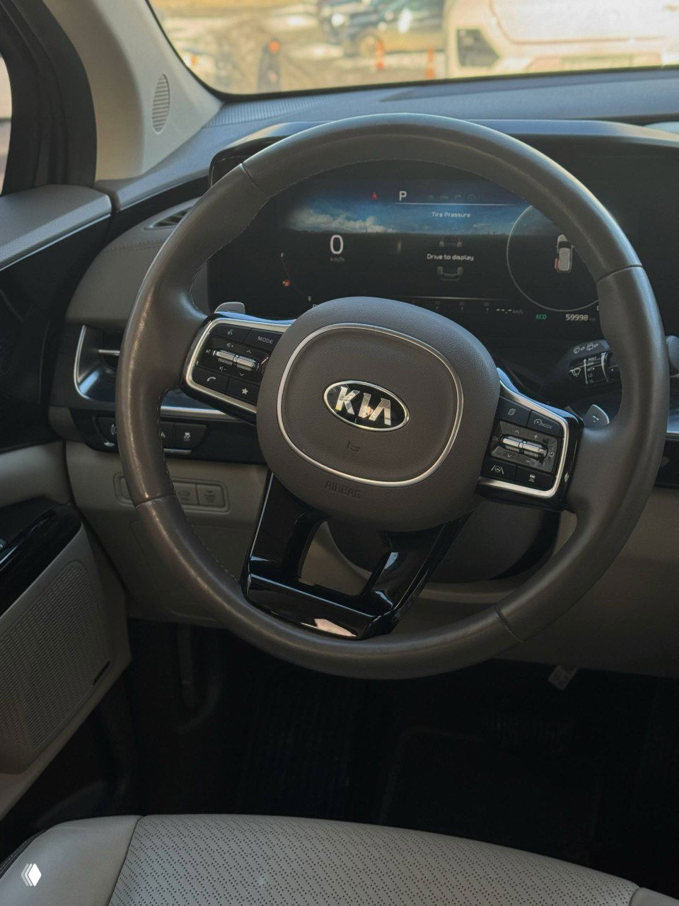 Рулевое колесо KIA с логотипом, цифровая панель приборов и элементы управления на руле, на экране виден пробег около 59998 км.
