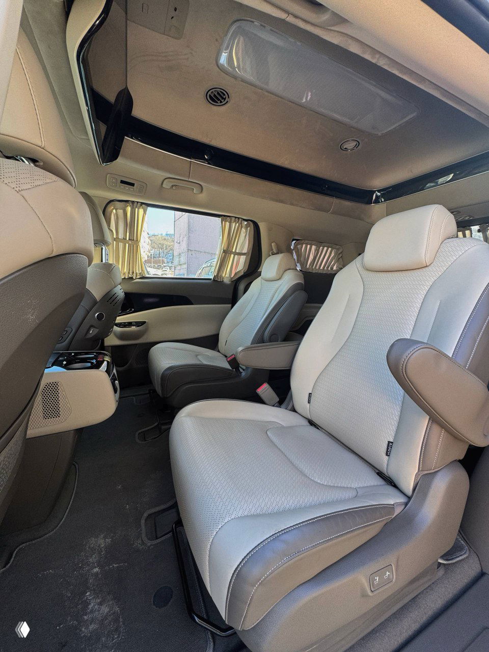 Второй ряд кресел минивэна KIA Carnival — два комфортабельных сиденья, потолочная отделка и шторы на окнах, интерьер для пассажиров второго ряда.