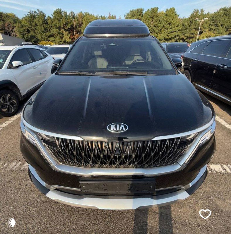 Фото KIA Carnival сзади на стоянке, видна задняя часть минивэна и номерной знак, автомобиль готовят к отгрузке на автовоз