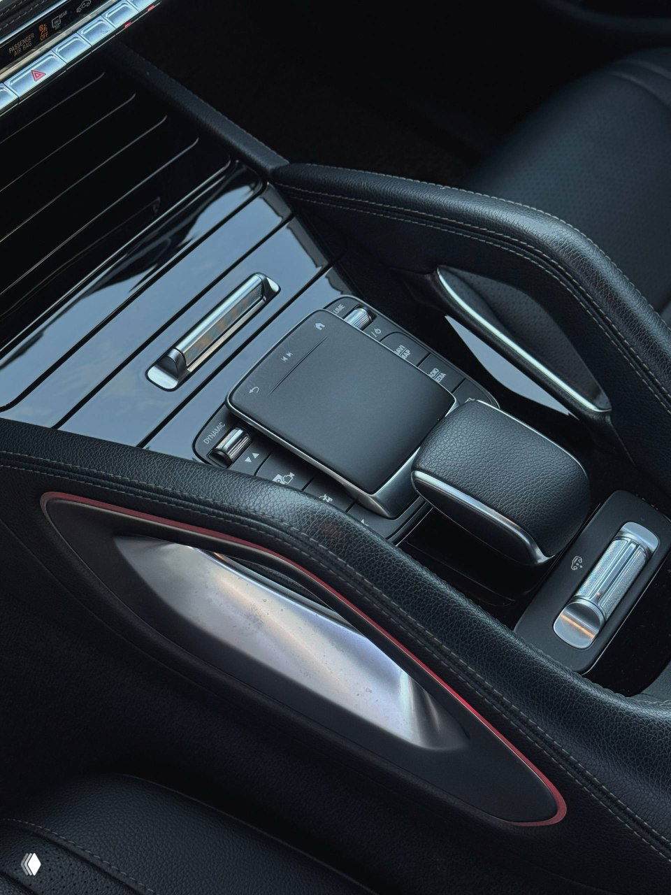 Крупный план центральной консоли Mercedes GLE300d: тачпад, рукоятка передачи и декоративные вставки, аккуратная отделка салона.