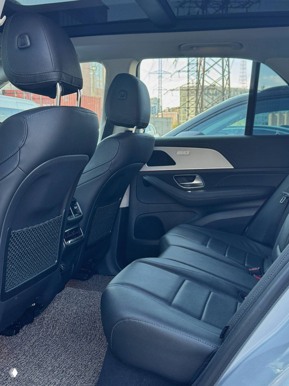 Задние сиденья салона Mercedes GLE300d: чёрная кожаная обивка, видны подголовники, пространство для пассажиров и задние карманы на передних сиденьях.