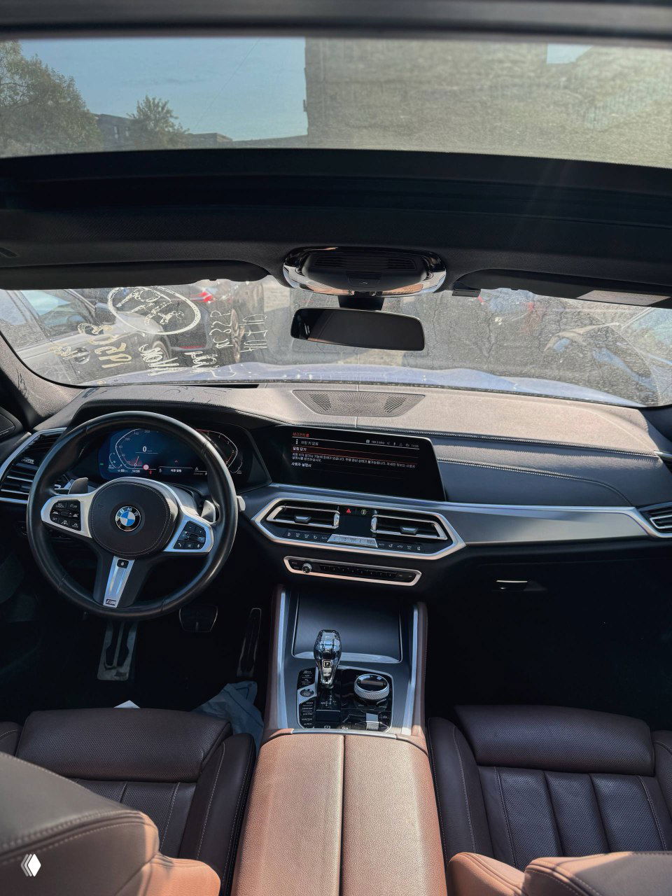 Вид салона BMW X6 с панорамной крышей, приборной панелью и центральным экраном; коричневая отделка сидений, фото демонстрирует состояние интерьера