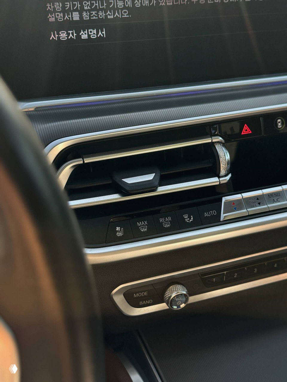 Крупный план центральной вентиляции и части мультимедийного экрана BMW X6; видны хромированные молдинги, кнопки климата и строки на корейском языке