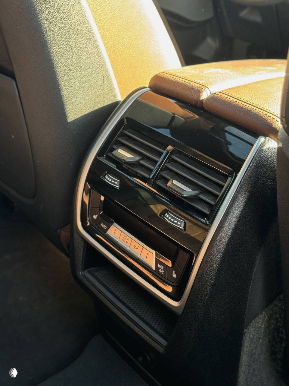 Задний ряд сидений BMW X6 в коричневой коже, видна отделка дверей, пространство для пассажиров и панель климат-контроля для задних мест