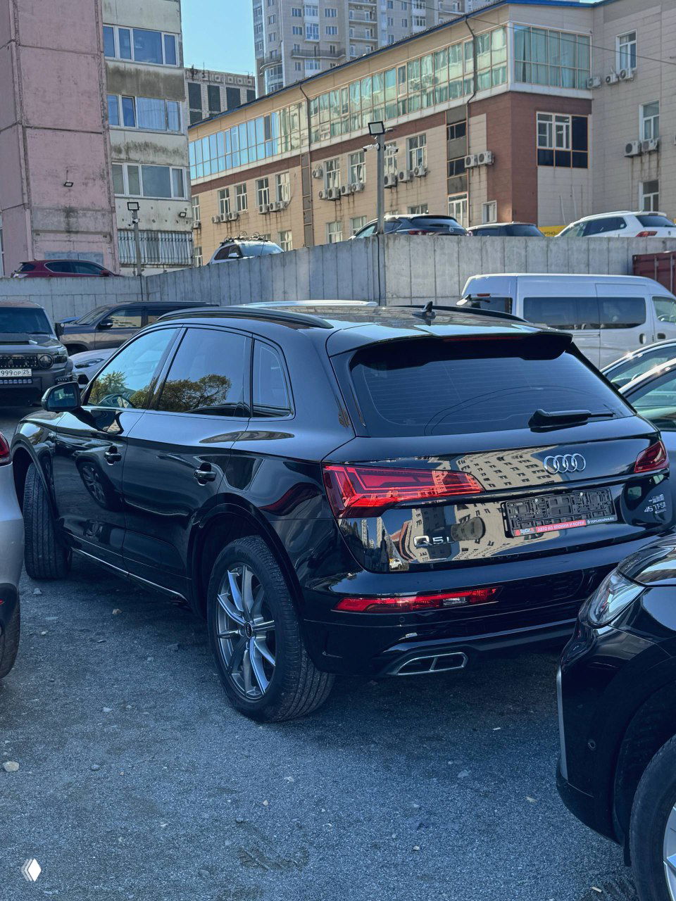 Вид сзади и сбоку: черный Audi Q5L, заметен удлиненный кузов Q5L, светодиодные фонари и двойные патрубки выхлопа в нижней части бампера