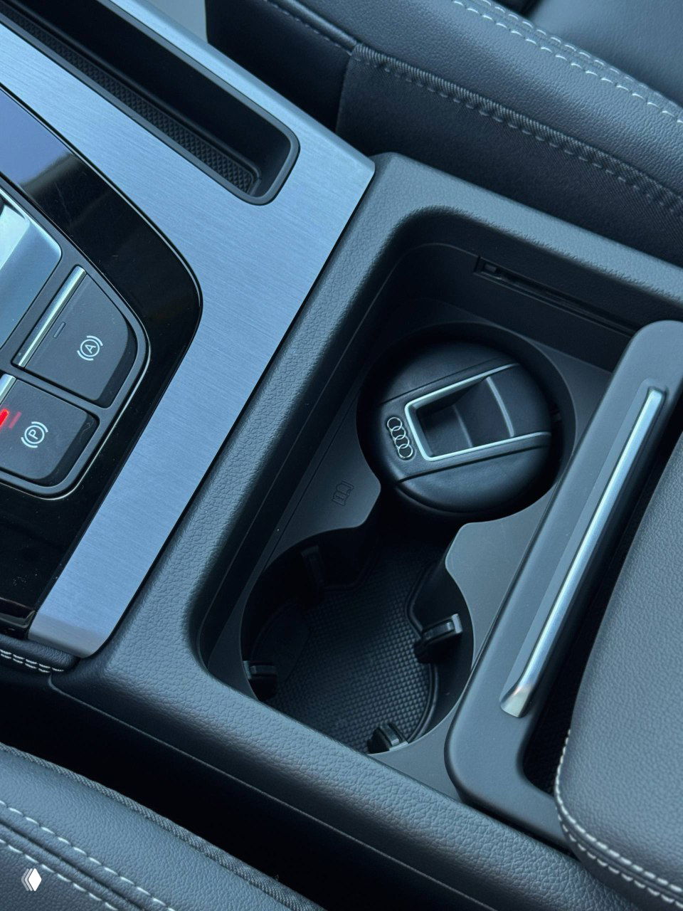 Подстаканник и место для мелочей в центральной консоли Audi Q5L, виден фирменный ключ Audi в углублении рядом с держателем для чашки