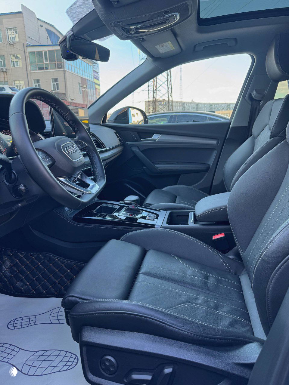 Интерьер передней части салона Audi Q5L: водительское кресло в коже, панорамный люк и аккуратная отделка дверных панелей и приборной панели