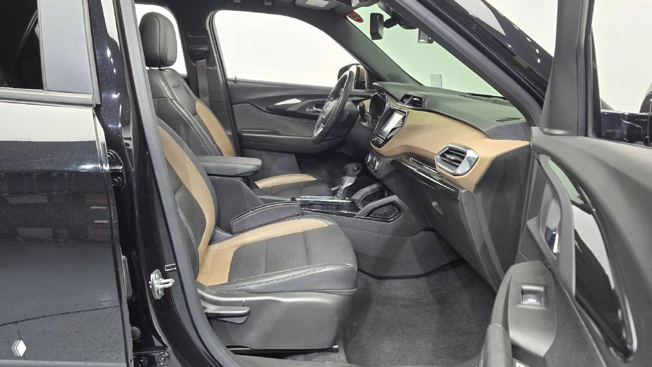 Передние кресла и пассажирская часть салона Chevrolet Trailblazer — чёрная и коричневая обивка, плотно и аккуратно, видна пассажирская дверь и пространство.