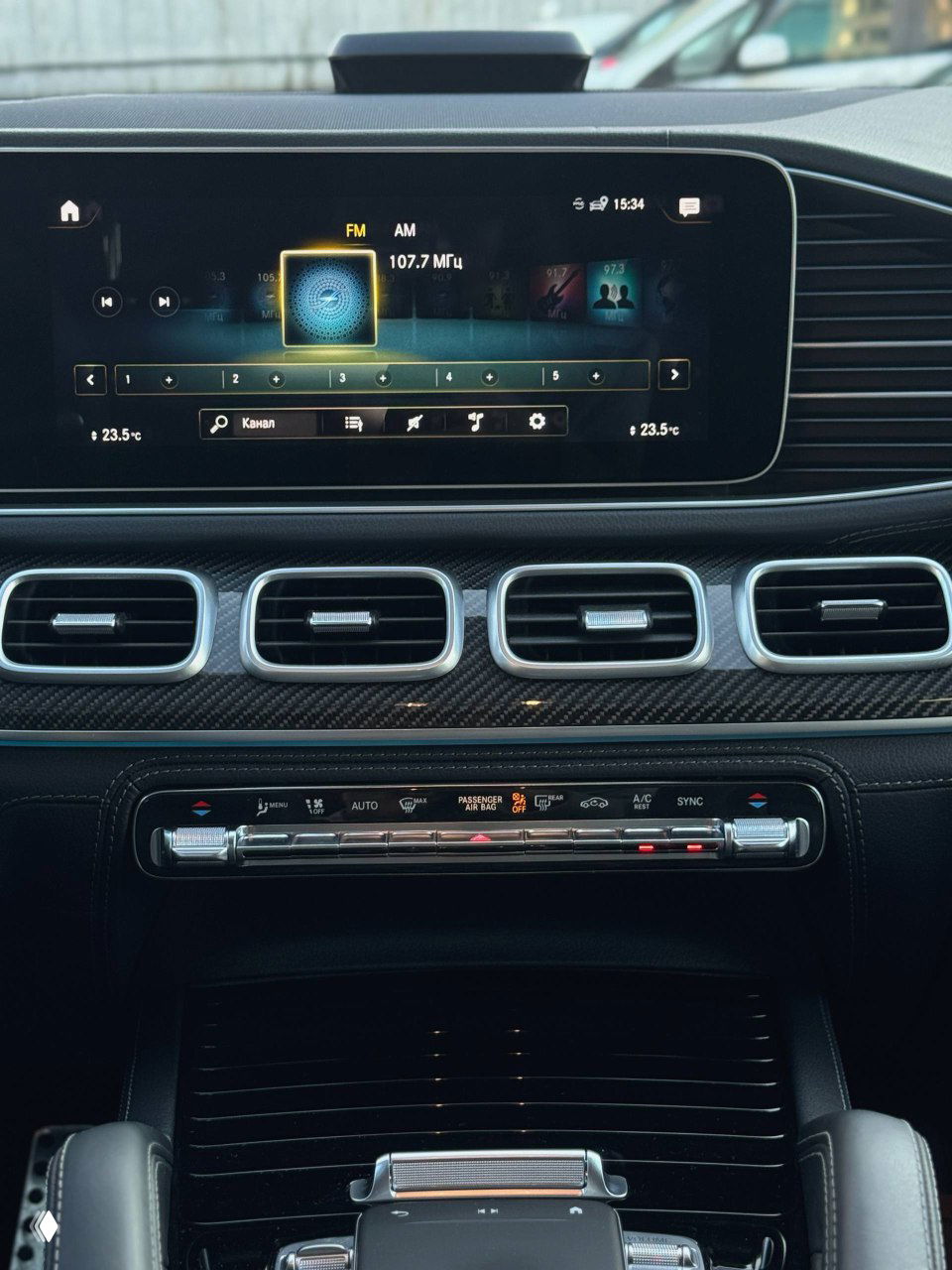 Мультимедийный дисплей и центральная панель Mercedes GLE53 AMG — экран с радиостанциями, вентиляционные дефлекторы и элементы климата в окантовке.