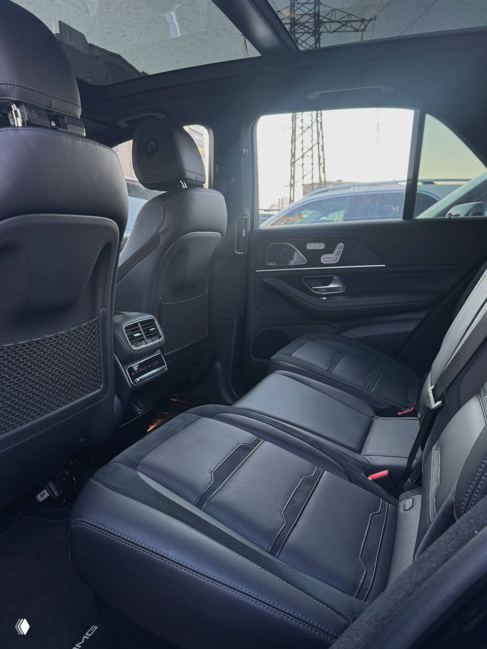 Салон Mercedes GLE53 AMG, вид на задние сиденья — кожа, вентиляционные решётки в центральной консоли и простор для пассажиров на заднем ряду.