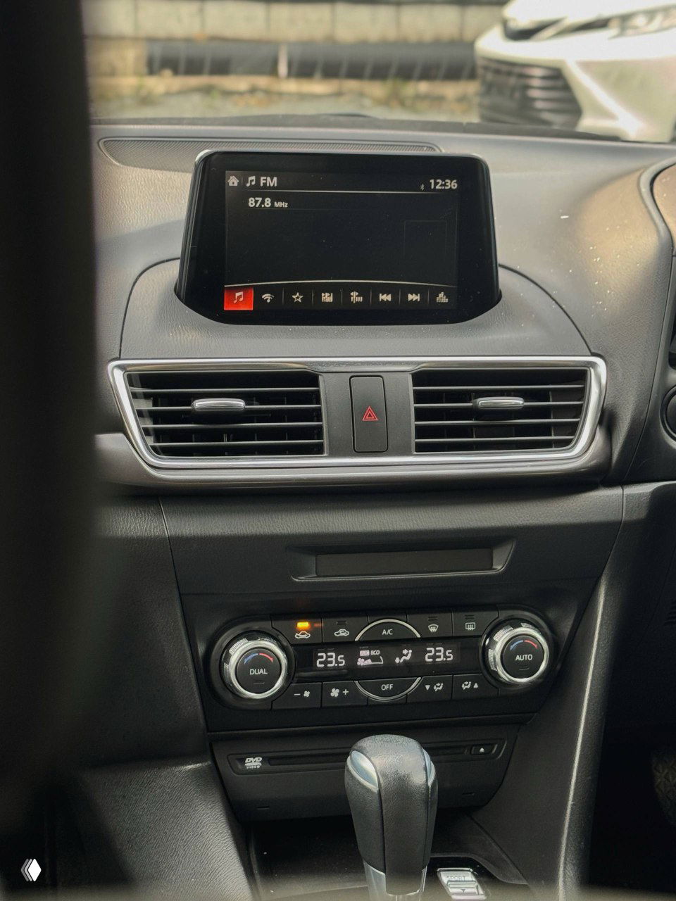 Центральная консоль Mazda Axela с мультимедийным экраном и воздуховодами — вид торпедо, экран включён на FM-частоту, общий вид панели.