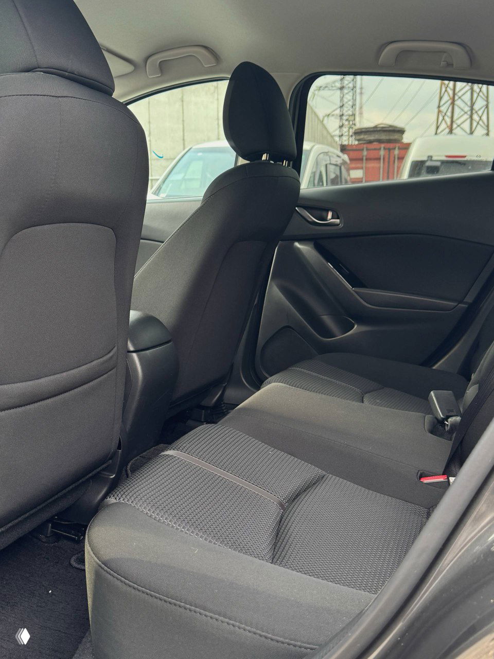 Задний ряд сидений Mazda Axela 2017 — торец пассажирского сиденья и место для двух пассажиров с текстильной обивкой, состояние без повреждений.