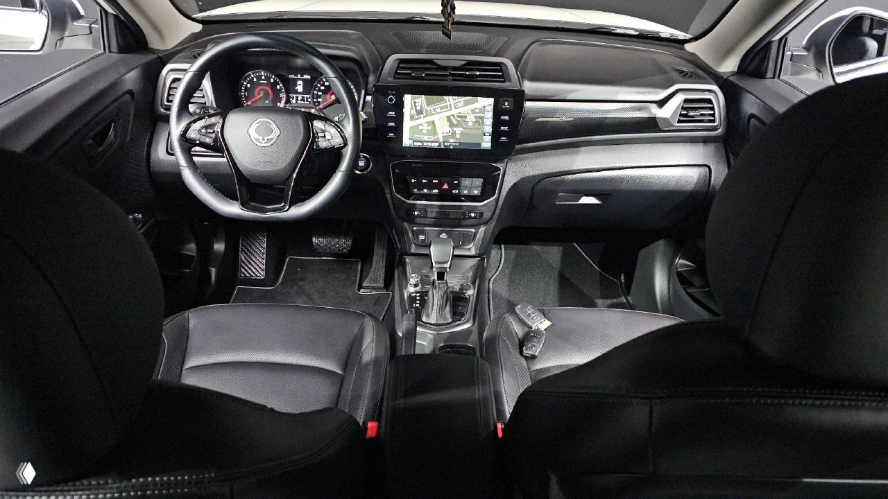Салон SsangYong Tivoli — панорамный вид на переднюю часть салона: руль, приборную панель, центральную консоль и передние кресла в кожаной отделке.