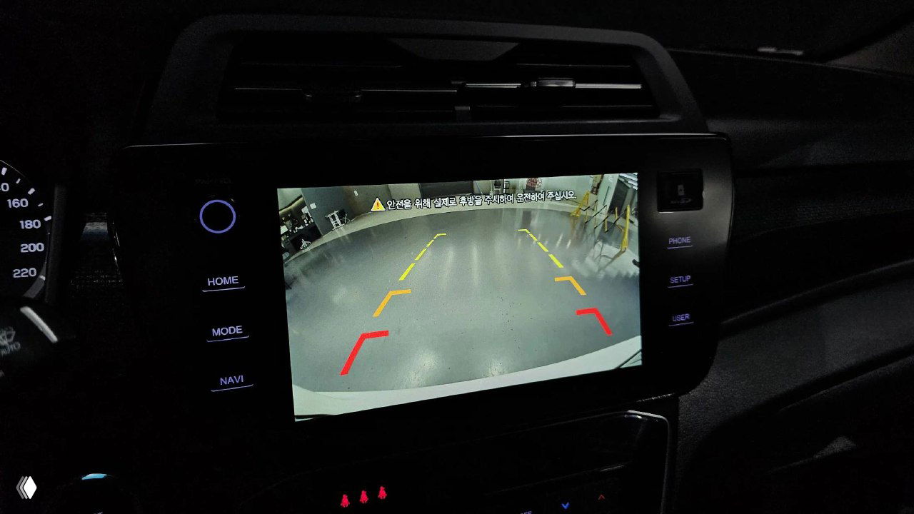 Камера заднего вида на экране центральной панели SsangYong Tivoli — парковочная разметка видна на экране в тёмном помещении автосалона.