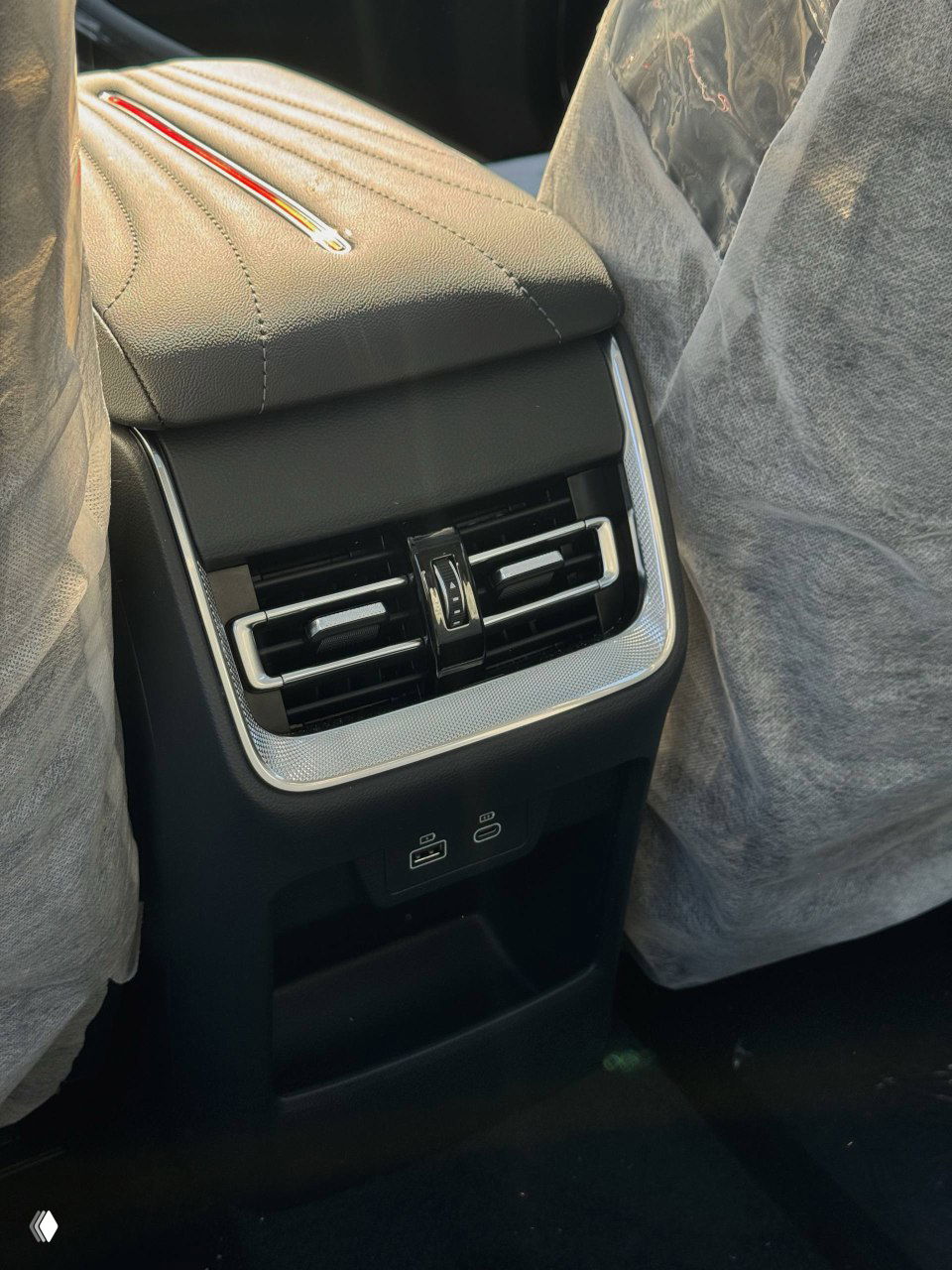 Детальный кадр задней части переднего подлокотника и декоративной строчки с фирменной отделкой Hongqi, видна текстура материалов.