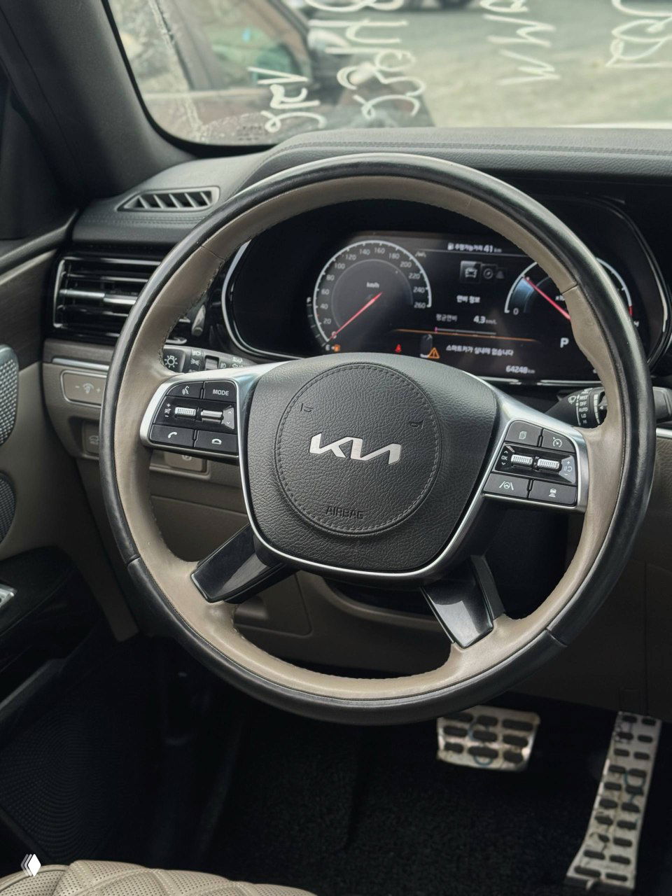 Салон KIA Mohave: вид на рулевое колесо с логотипом KIA, приборную панель и часть переднего пассажирского пространства.