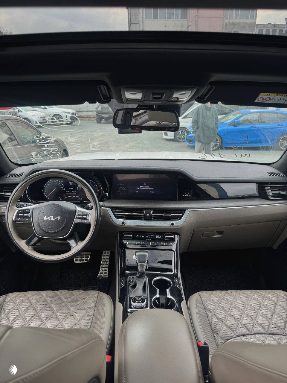 Широкий вид на переднюю панель и салон KIA Mohave со стороны лобового стекла: рулевое колесо, экран и передние сиденья.