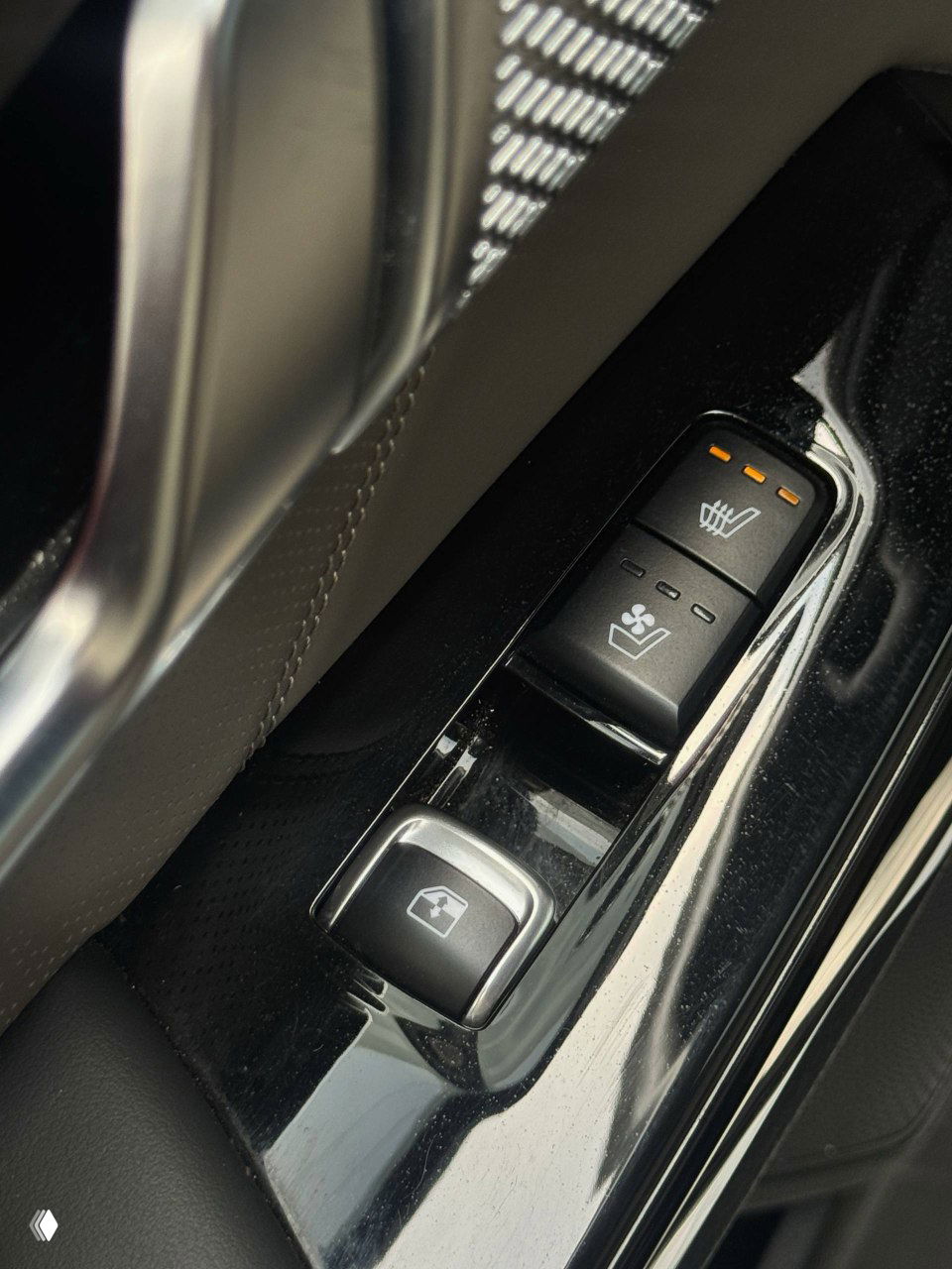 Крупный план кнопок управления стеклоподъёмниками и вентиляции сиденья в двери KIA Mohave, вид на хромированные элементы и динамик.