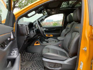 Передние сиденья салона Ford Ranger 2023 в чёрной коже с контрастной прострочкой, виден интерьер, панорамная крыша и элементы дверного полотна.