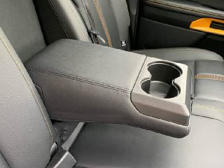 Складной подлокотник с подстаканниками и швами на материалах в задней части салона Ford Ranger, крупный план отделки и функционала.