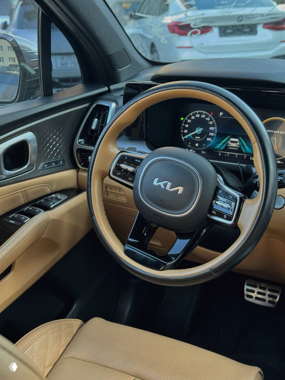 Интерьер KIA Sorento — рулевое колесо в бежевой коже, панель приборов и мультимедиа, крупный план салона переднего ряда и элементы управления.