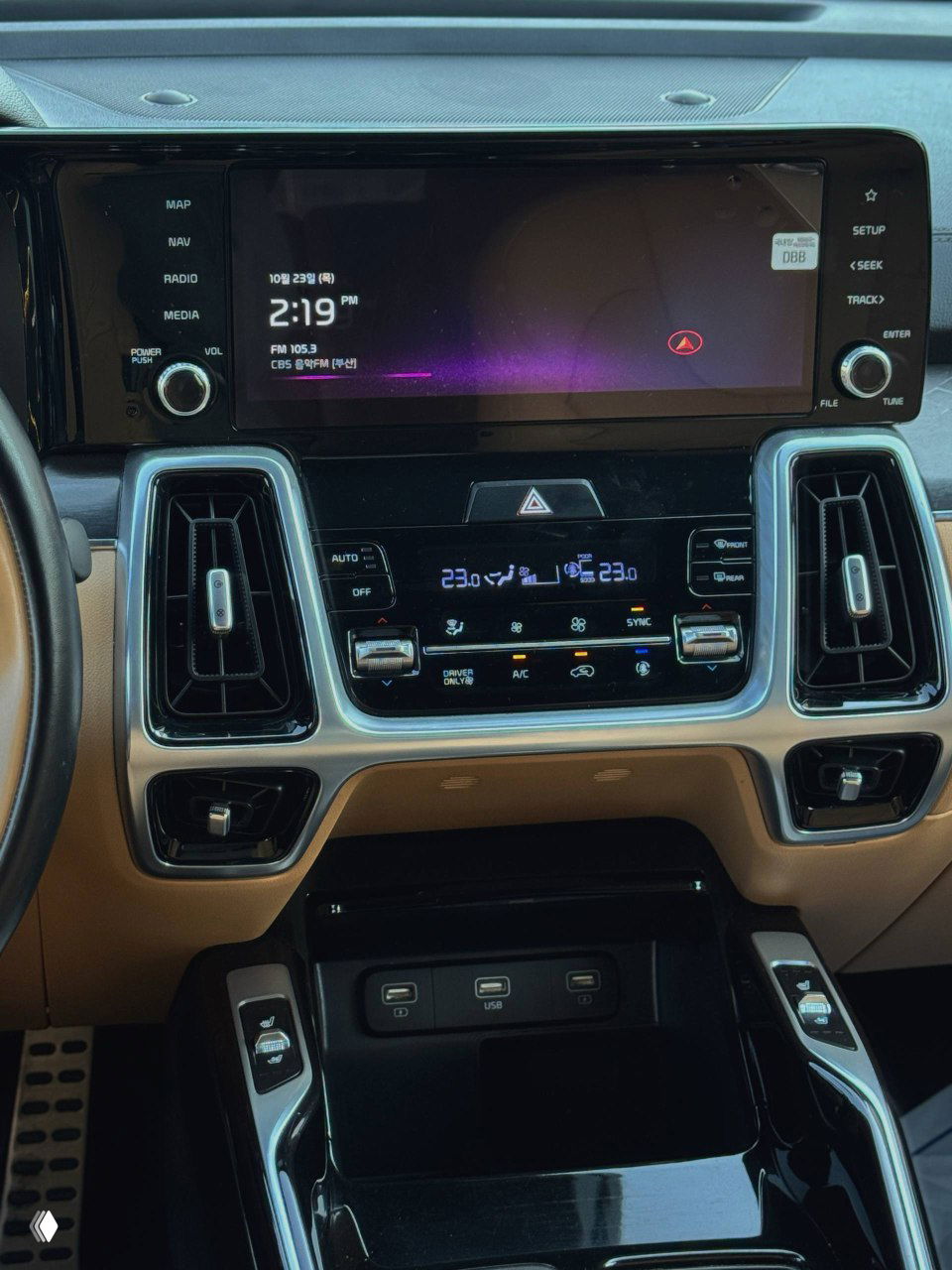 Центральная консоль KIA Sorento — мультимедийный экран и блок климат-контроля, крупный план кнопок и дисплея с подсветкой, бежевый интерьер.