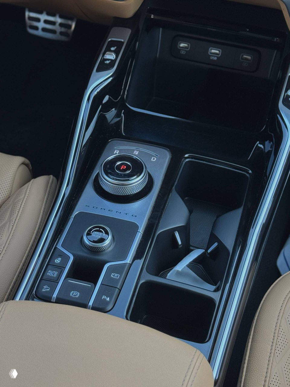 Селектор и центральный тоннель KIA Sorento — вращающийся селектор передач, подстаканники и глянцевые чёрные вставки, вид на отделку салона.