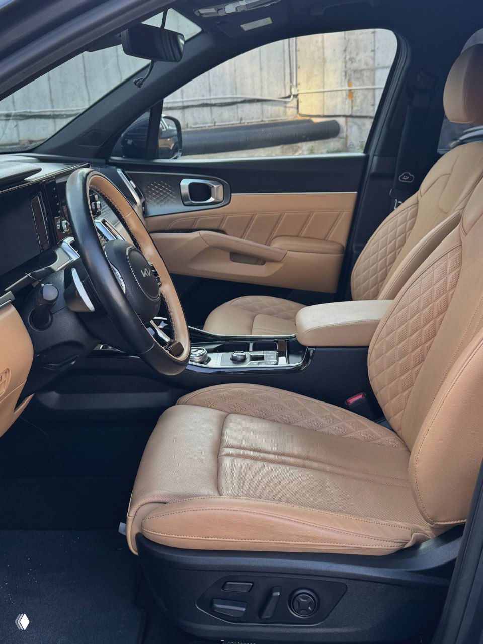 Вид переднего пассажирского места KIA Sorento — бежевые кожаные сиденья с декоративной прострочкой, панорамный вид на переднюю часть салона.