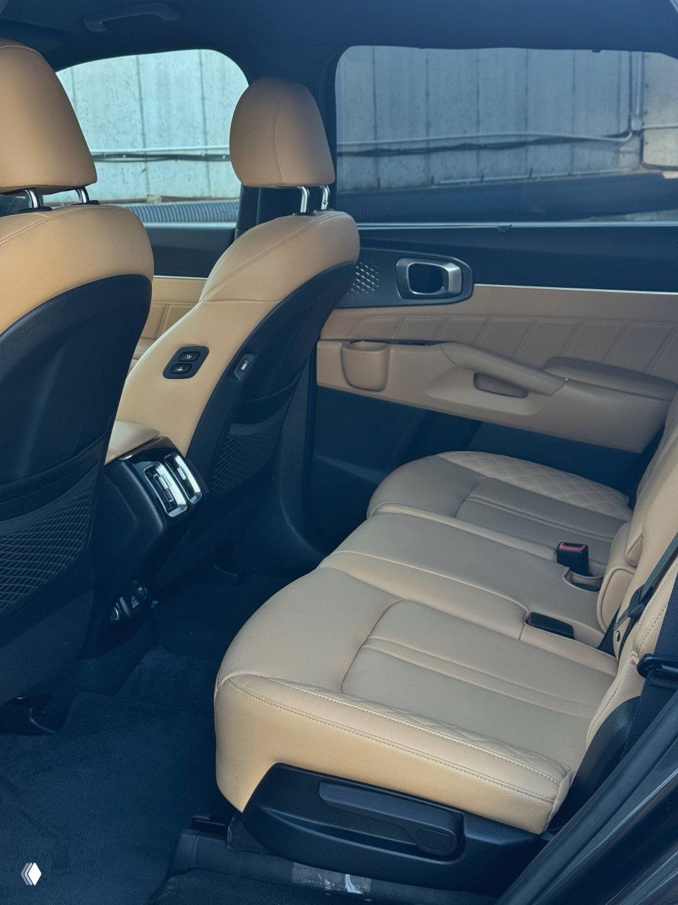 Задний ряд сидений KIA Sorento — бежевый салон, простор для пассажиров и вентиляционные дефлекторы на центральной консоли заднего ряда, общий вид.