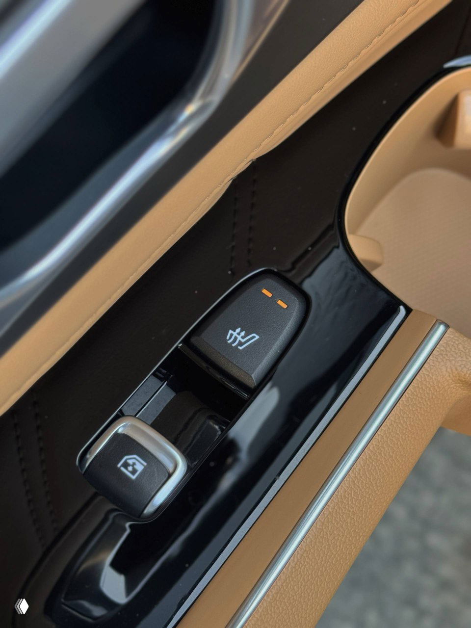 Крупный план кнопки подогрева и управления стеклоподъёмником на дверной панели KIA Sorento — бежево-чёрная отделка и хромированные акценты.