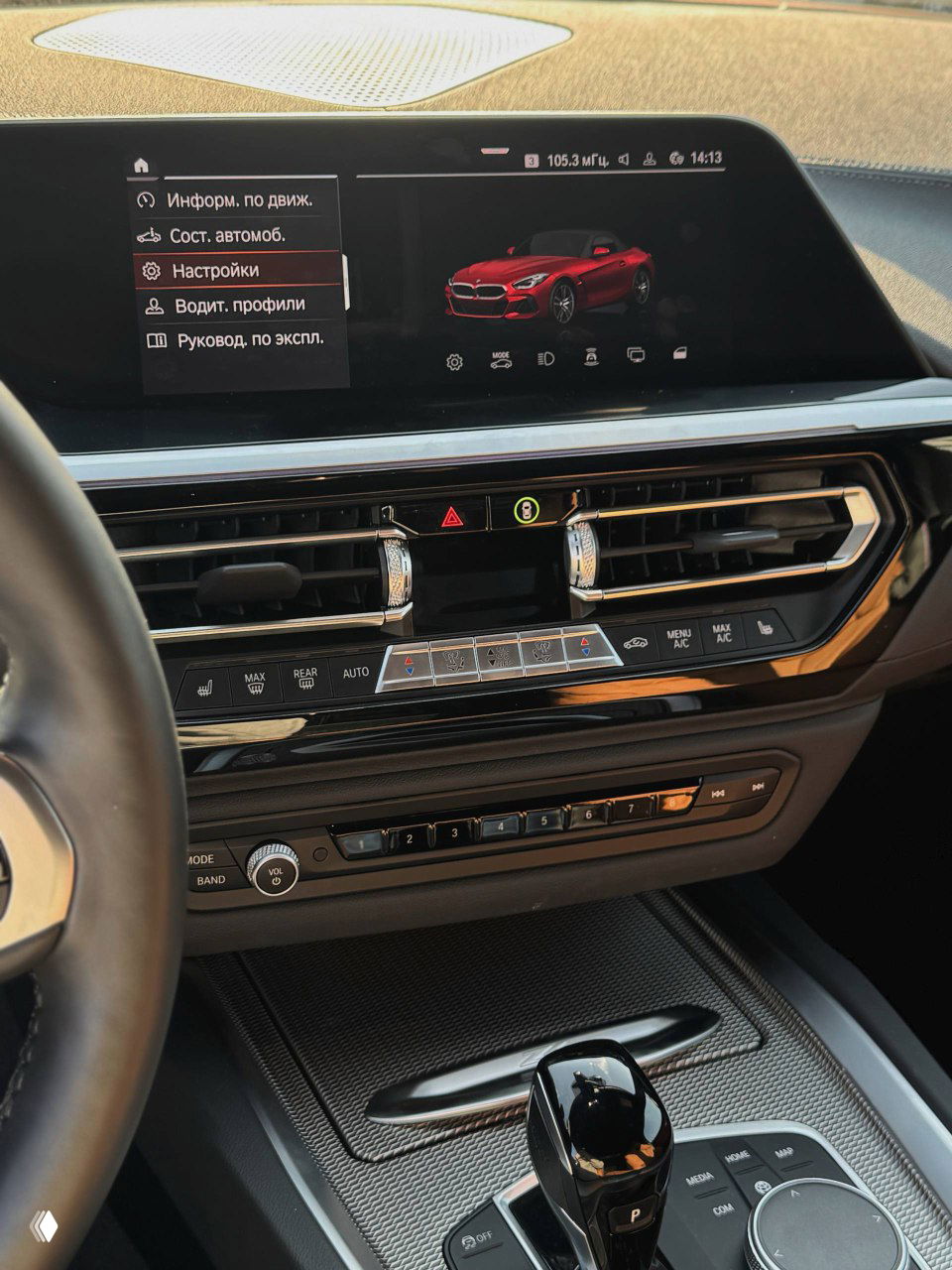 Информационный экран мультимедиа BMW с изображением автомобиля, элементы управления климатом и декоративная панель на приборной доске.