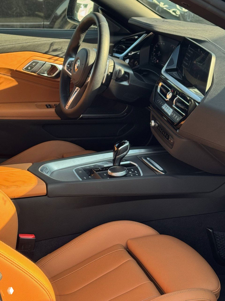 Вид на водительскую дверь BMW с панелью управления стеклоподъёмниками и кнопками памяти сиденья, коричневая кожаная отделка.