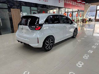Задний три четверти ракурс белого Honda Life 2021 в салоне, видно форму задних фонарей, заднюю часть кузова и интерьер через стекло.