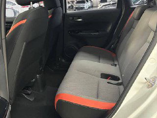 Задний ряд сидений Honda Life 2021 с такой же серо-оранжевой обивкой, трехместная скамья, видно место для ног и ремни безопасности.