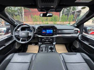 Интерьер Ford F-150 Raptor: широкий вид на переднюю панель, мультимедийный экран и руль, салон с кожаными вставками и центральным тоннелем.