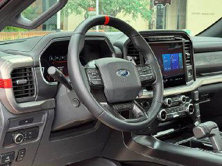 Крупный план руля и части приборной панели Ford F-150 Raptor, видно многофункциональное управление на руле, декоративные вставки и центральный экран.